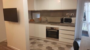 A compact kitchen with white cabinets, a built-in oven, a microwave, and a sink.