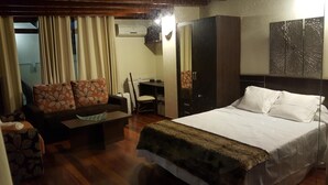 A hotel room with a bed, a sofa with floral cushions, a desk, a wardrobe, and a decorative wall piece. - Luxury Loft in Gran Canaria. Jacuzzi and Free WIFI. (Sta Brígida)