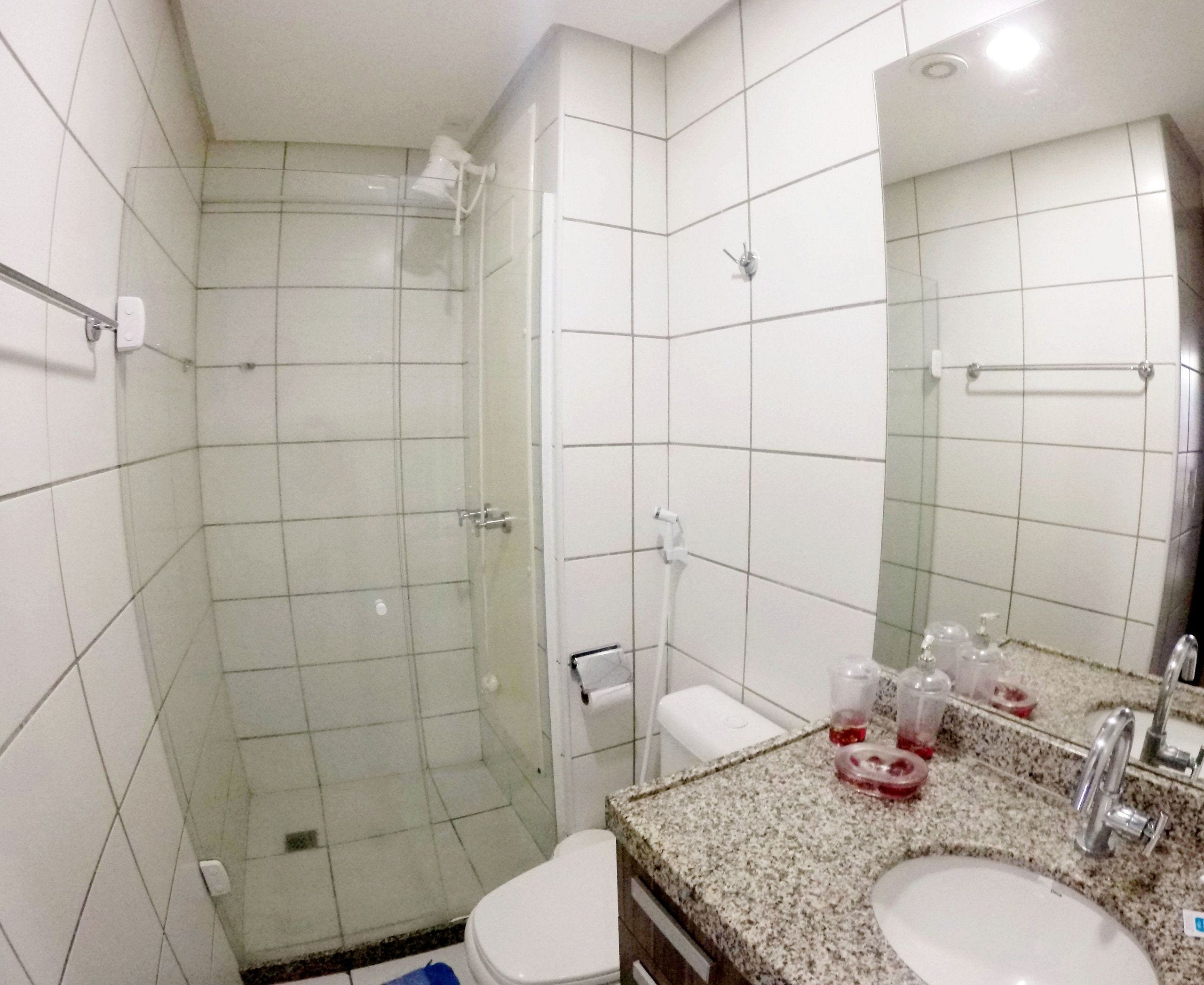 A bathroom with a shower, toilet, sink, and mirror.