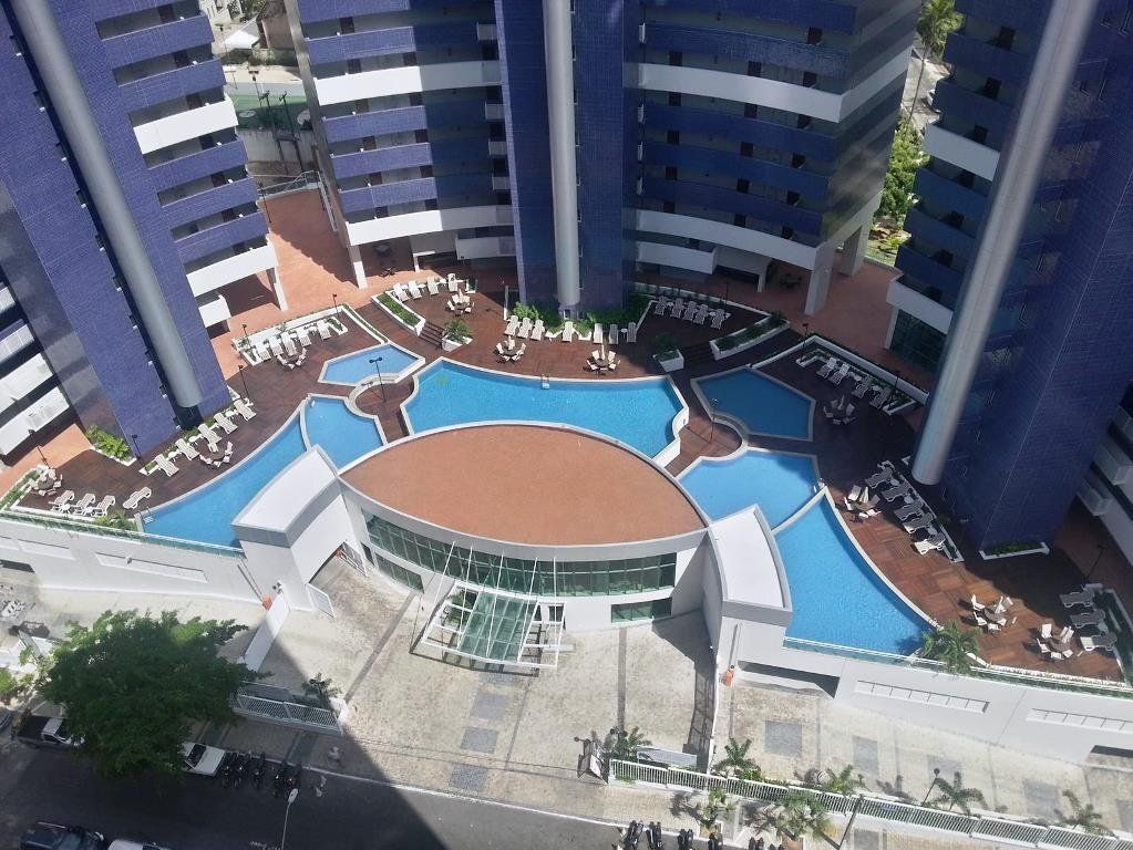 Un hotel moderno de gran altura con varios balcones, una piscina central y zonas de estar al aire libre.
