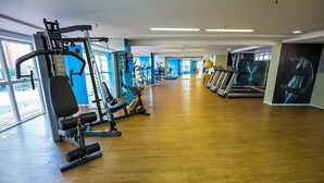 A gym with cardio machines, weightlifting equipment, and a wooden floor. - Beach Class Residence by SOLEMAR (Fortaleza)
