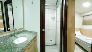 A bathroom with a sink, mirror, shower, and a bed. - Beach Class Residence by SOLEMAR (Fortaleza)