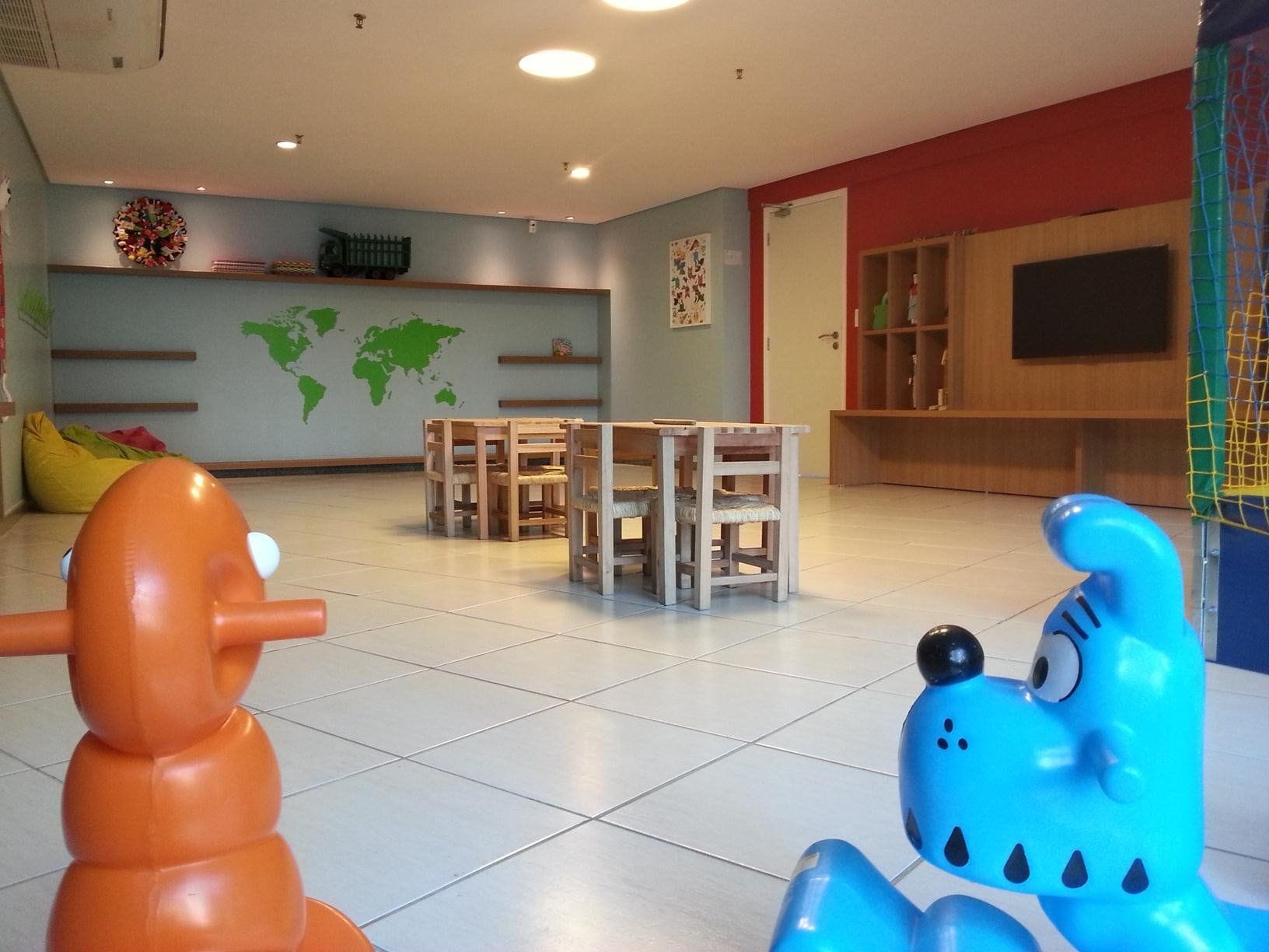 Une pièce avec une carte du monde accrochée au mur, une télévision et un espace de jeux avec des jouets.
