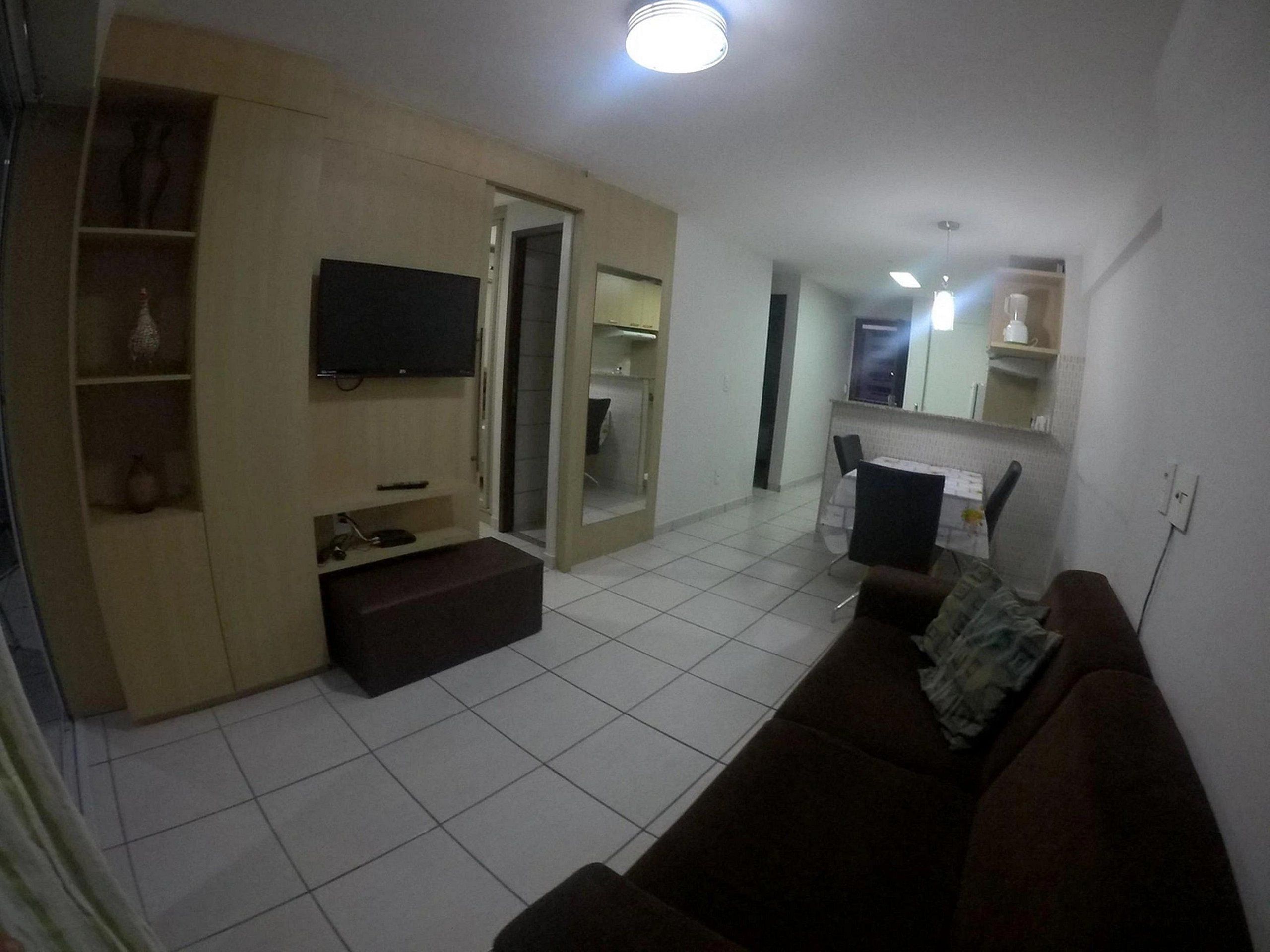 Una sala de estar con televisor, sofá, mesa de centro y un comedor con sillas y mesa.