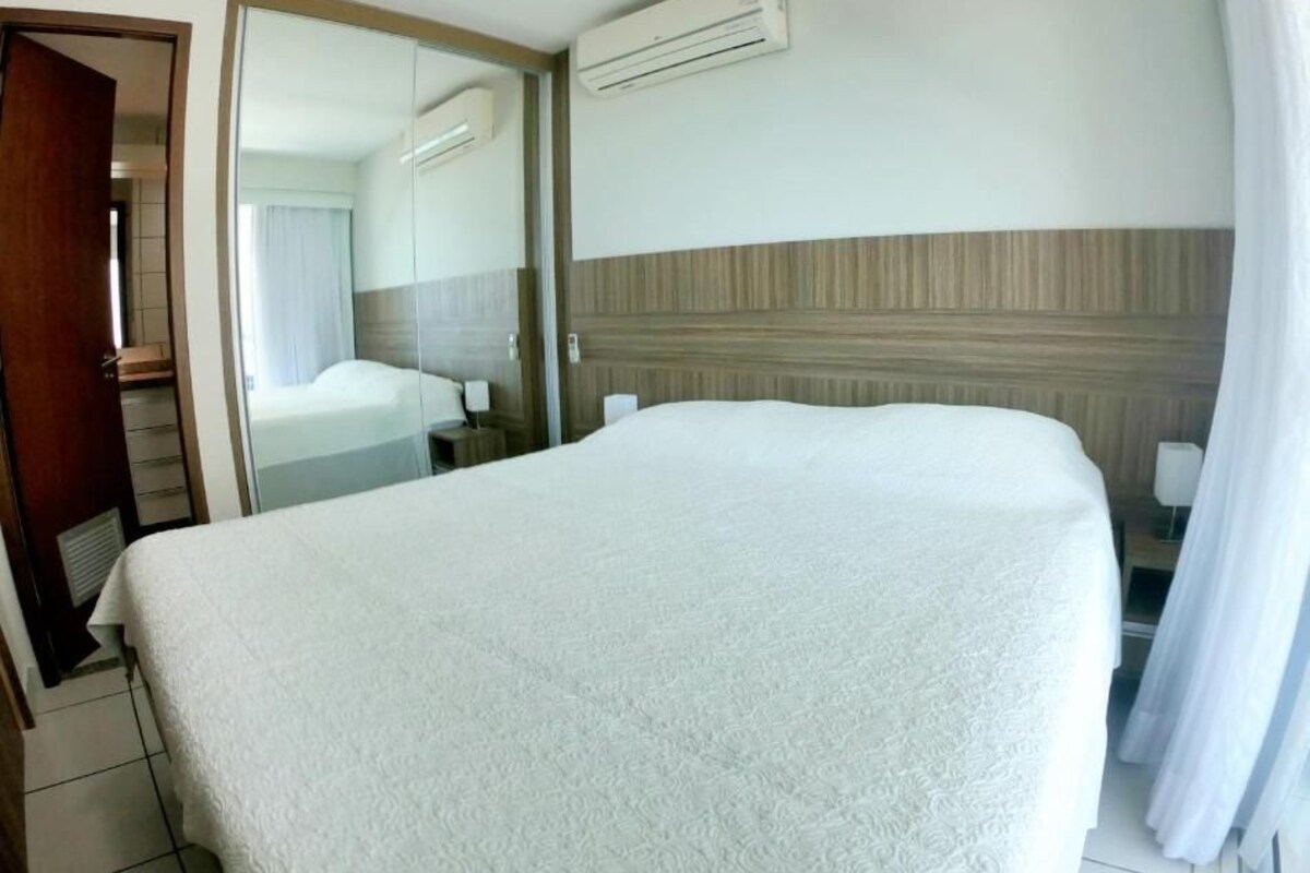 Ein Hotelzimmer mit Bett, Spiegel, Klimaanlage und einem Holzkopfteil.