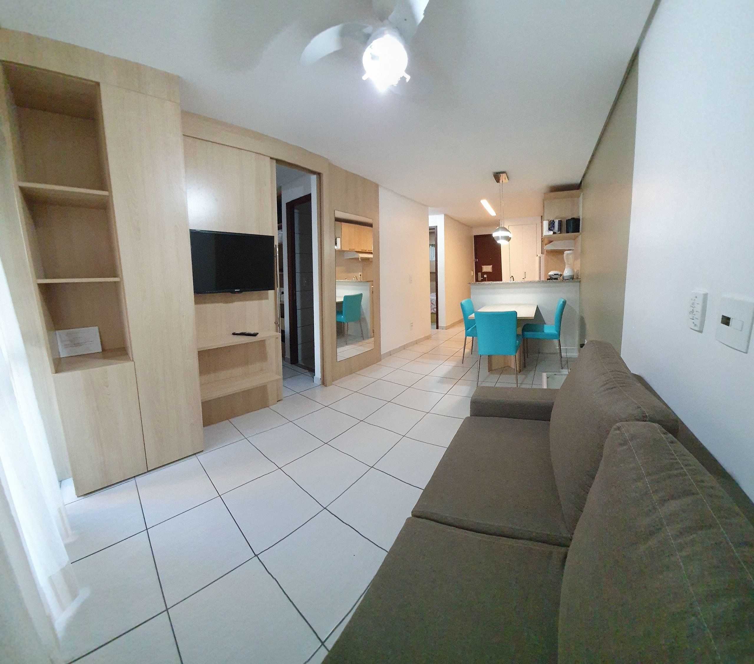 A living room with a sofa, a TV, and a dining area with chairs.