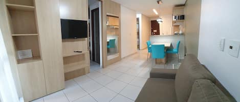 A living room with a sofa, a TV, and a dining area with chairs.