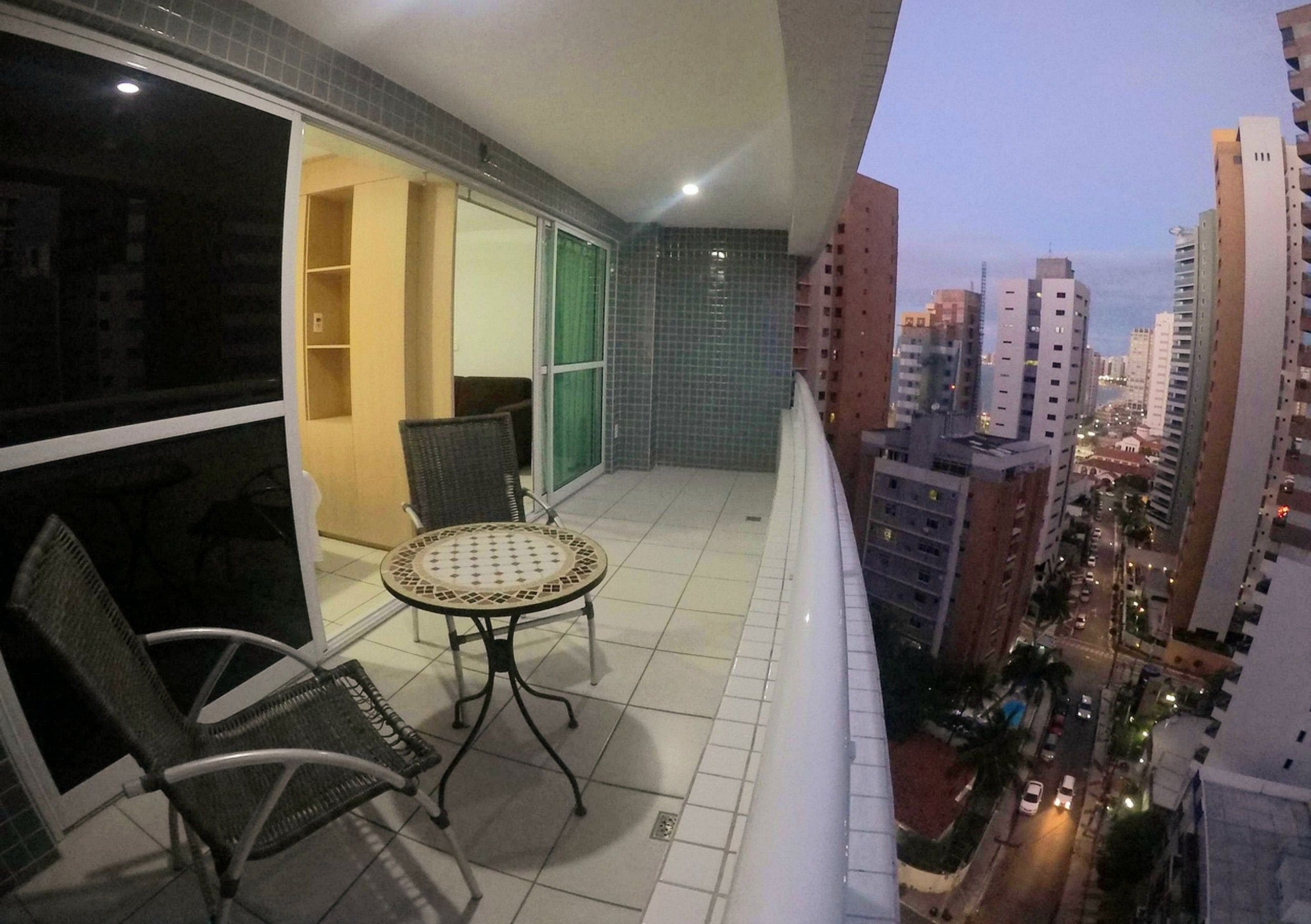 A balcony with a table and chairs, a sliding door, and a city view.