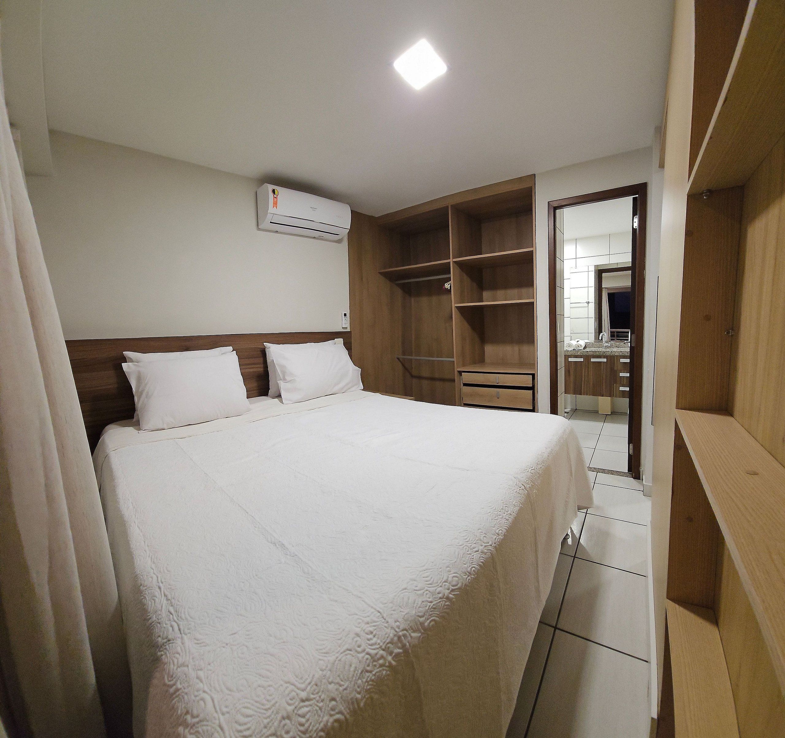 A hotel room with a bed, a wardrobe, and a bathroom visible through an open door.