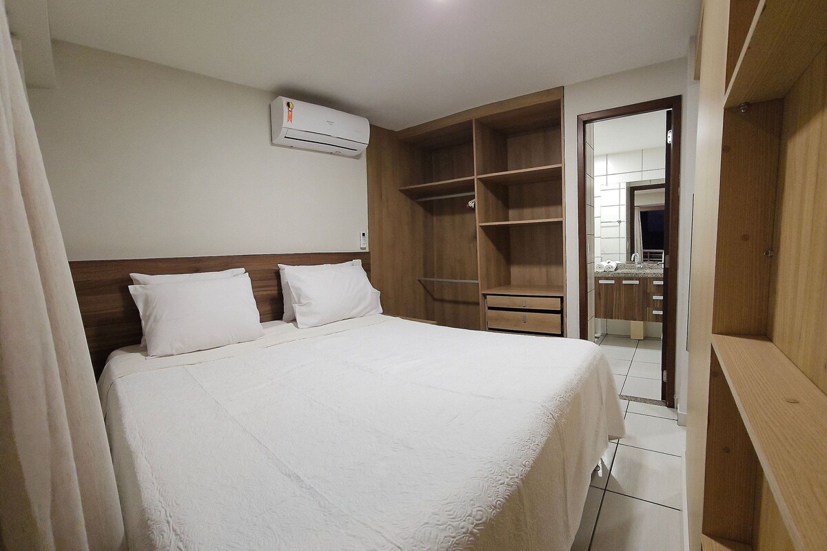 A hotel room with a bed, a wardrobe, and a bathroom visible through an open door.