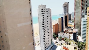 A high-rise building with a grid-like facade, a view of a beach, and other surrounding buildings. - Beach Class Residence by SOLEMAR (Fortaleza)