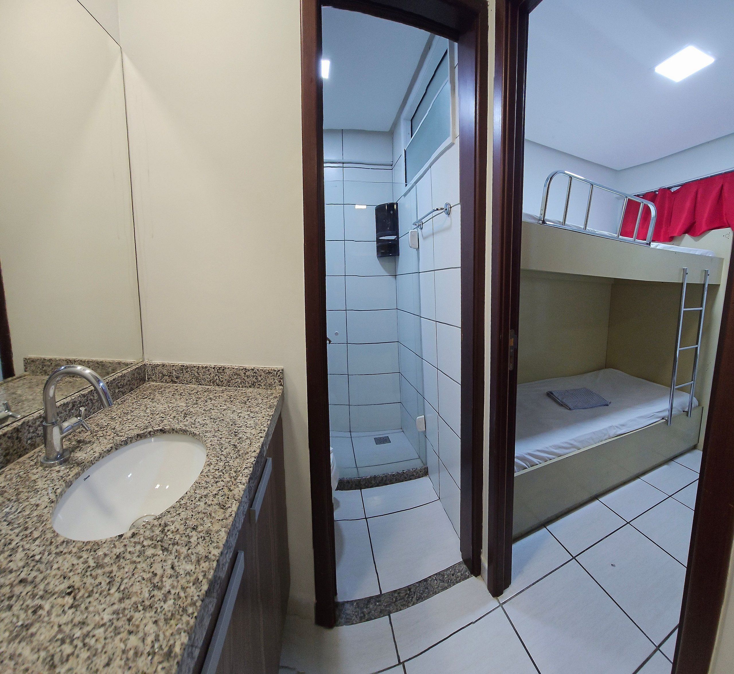 Un baño con lavamanos de encimera de granito, zona de ducha y una litera con escalera.