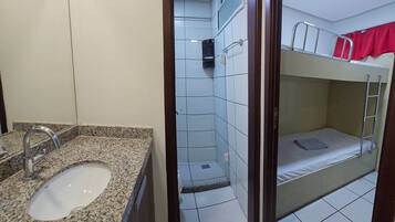 Un baño con lavamanos de encimera de granito, zona de ducha y una litera con escalera.