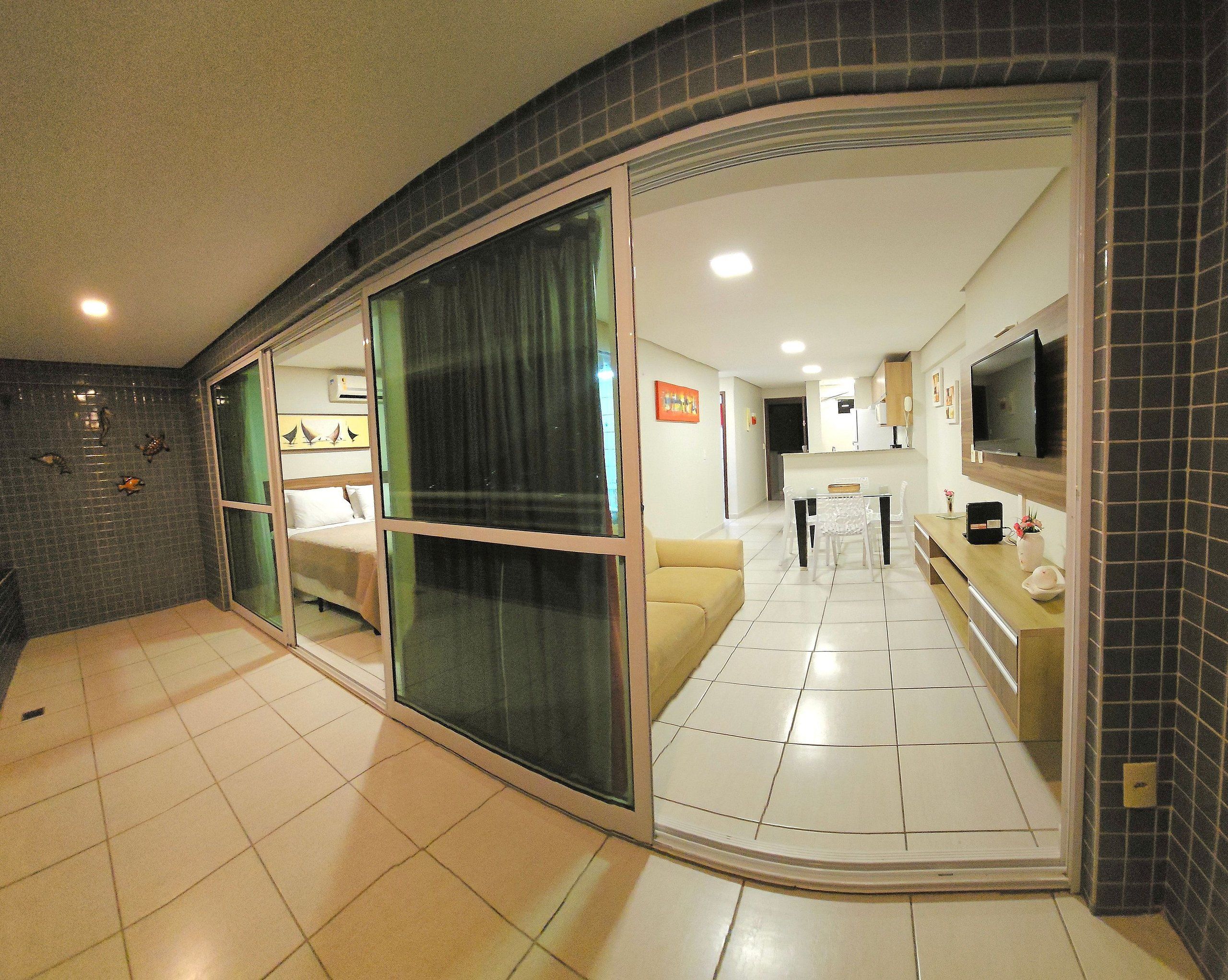 A modern interior with a kitchen, dining area, and living space, featuring sliding glass doors and tiled flooring.