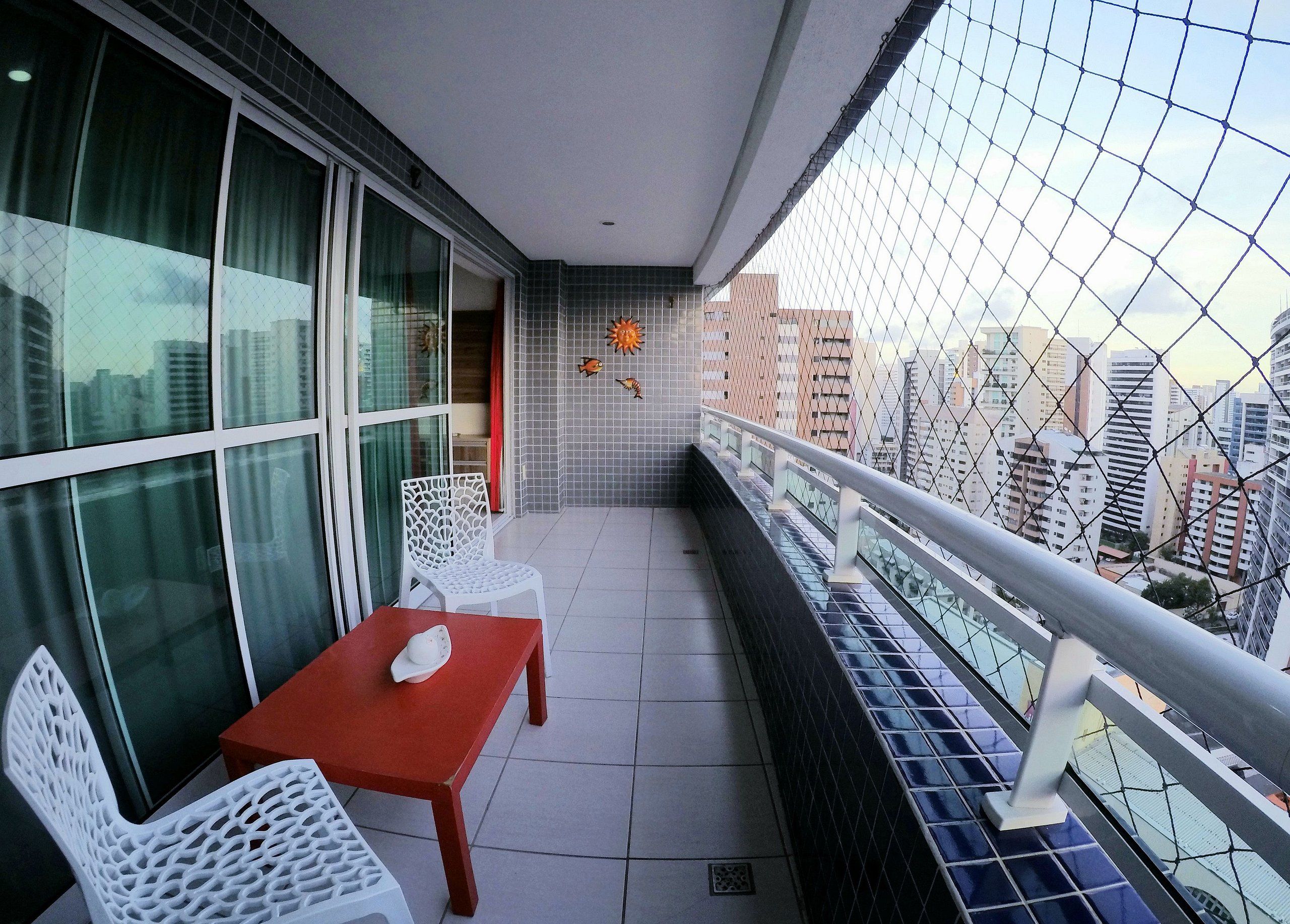 Ein Balkon mit Tisch und Stühlen und Blick auf die Stadt, an einer gefliesten Wand.