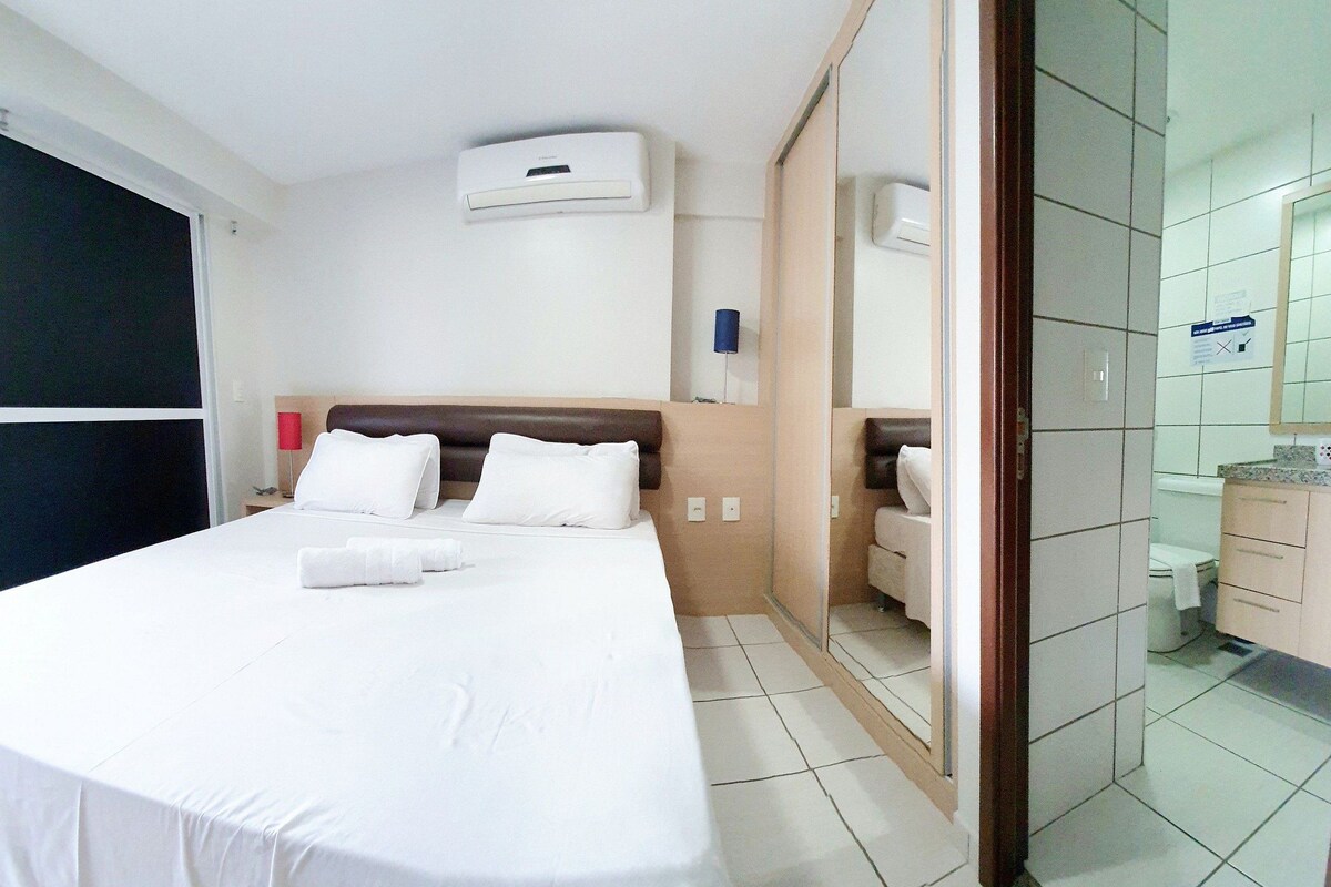 A hotel room with a bed, bedside table, and a bathroom visible through an open door.