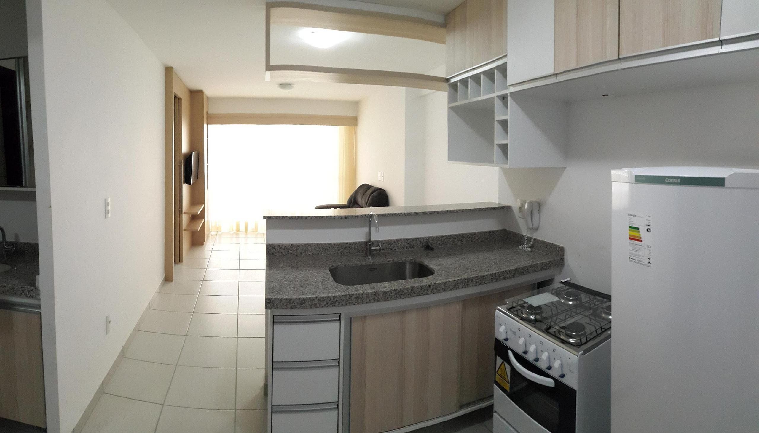A kitchen with a granite countertop, stainless steel sink, and a gas stove.
