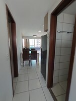 A hallway with a dining area, a view of a building, and a tiled floor.