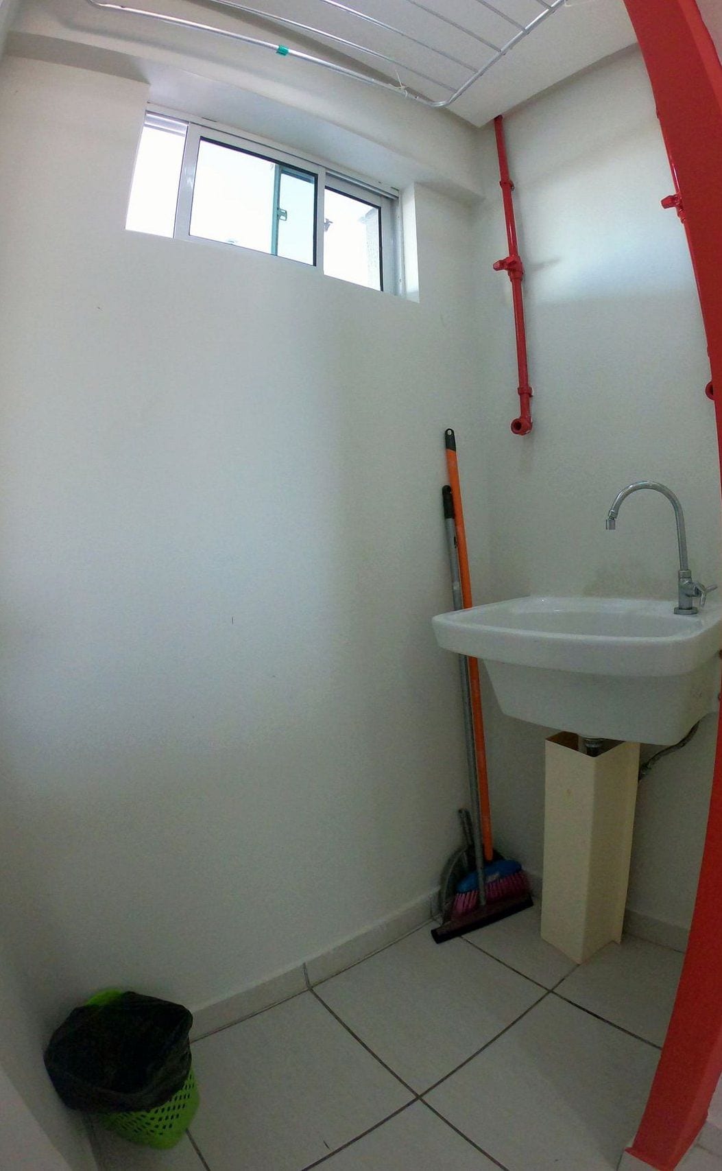 Une salle de bain avec une fenêtre, un lavabo et des produits de nettoyage.
