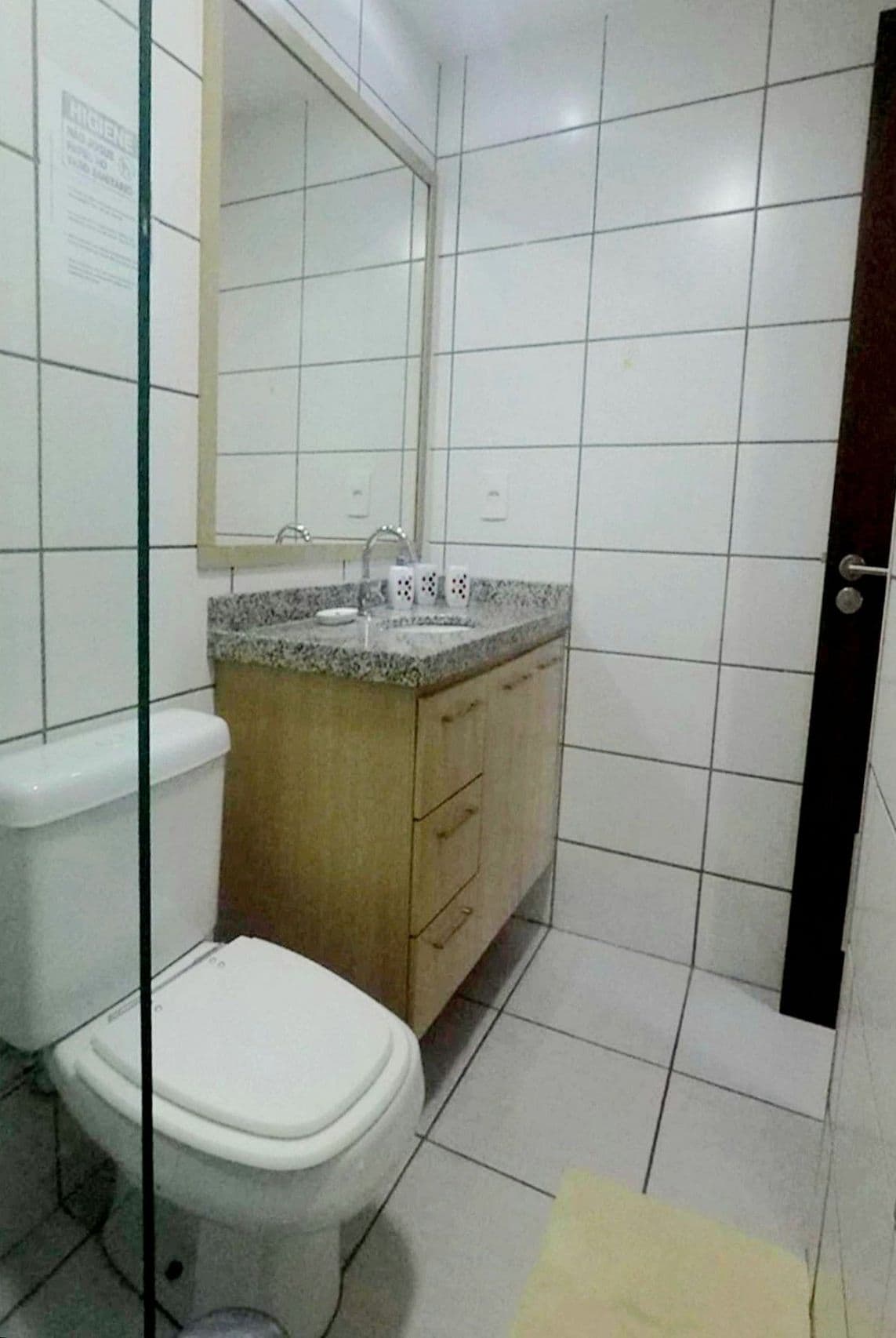 Een badkamer met toilet, wastafel, spiegel en betegelde wanden.