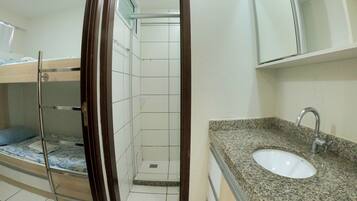 A bathroom with a sink, mirror, and shower.