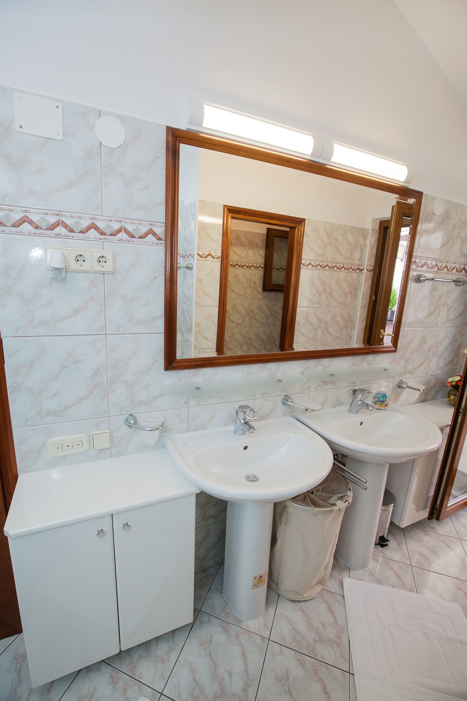 Een badkamer met twee wasbakken, een spiegel en een kast.