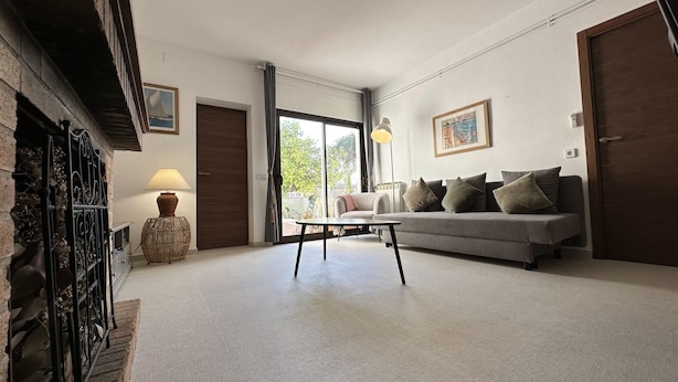 Ein geräumiges Wohnzimmer mit grauem Sofa, einem Couchtisch und einem Deckenventilator.