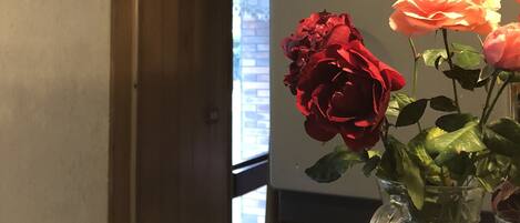 A restaurant sign, a vase with roses, and a window in the background.