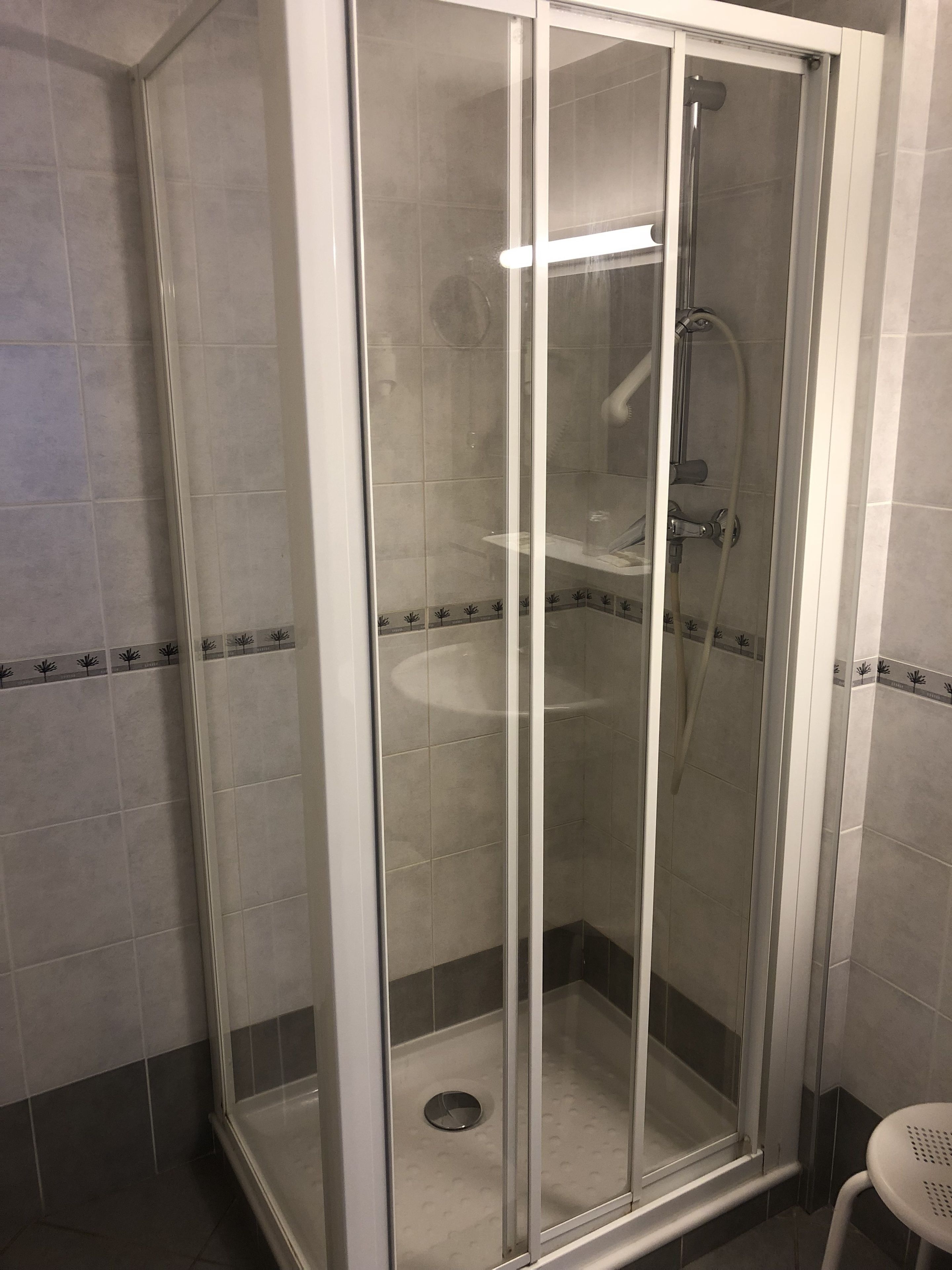 A glass-enclosed shower stall with a built-in sink and a handheld showerhead.