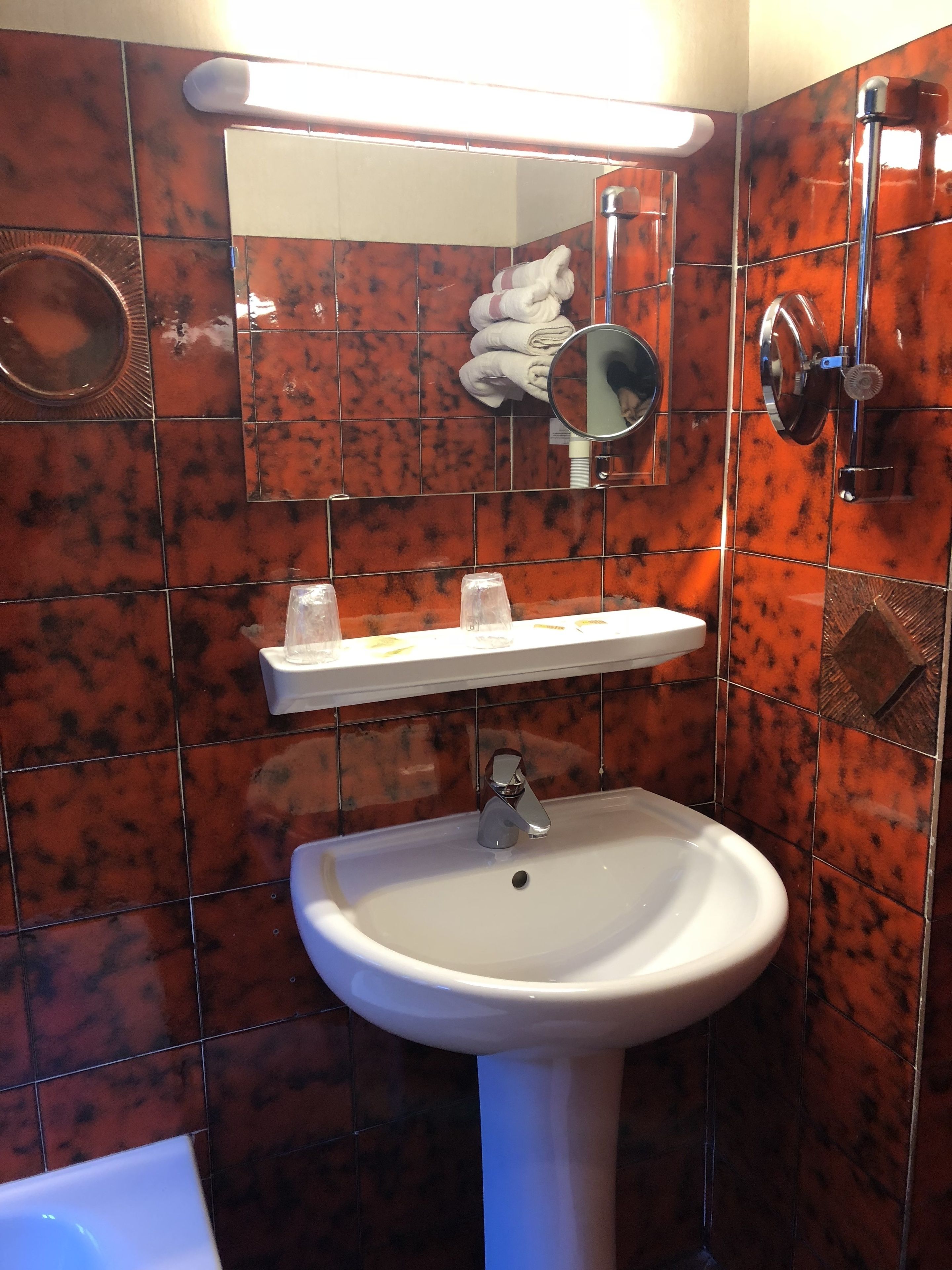 A bathroom with a white pedestal sink, a mirror above it, and a towel rack with folded towels.