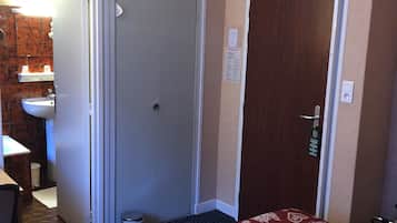 Habitación de hotel con dos camas, un baño con lavamanos y una puerta a otra habitación.