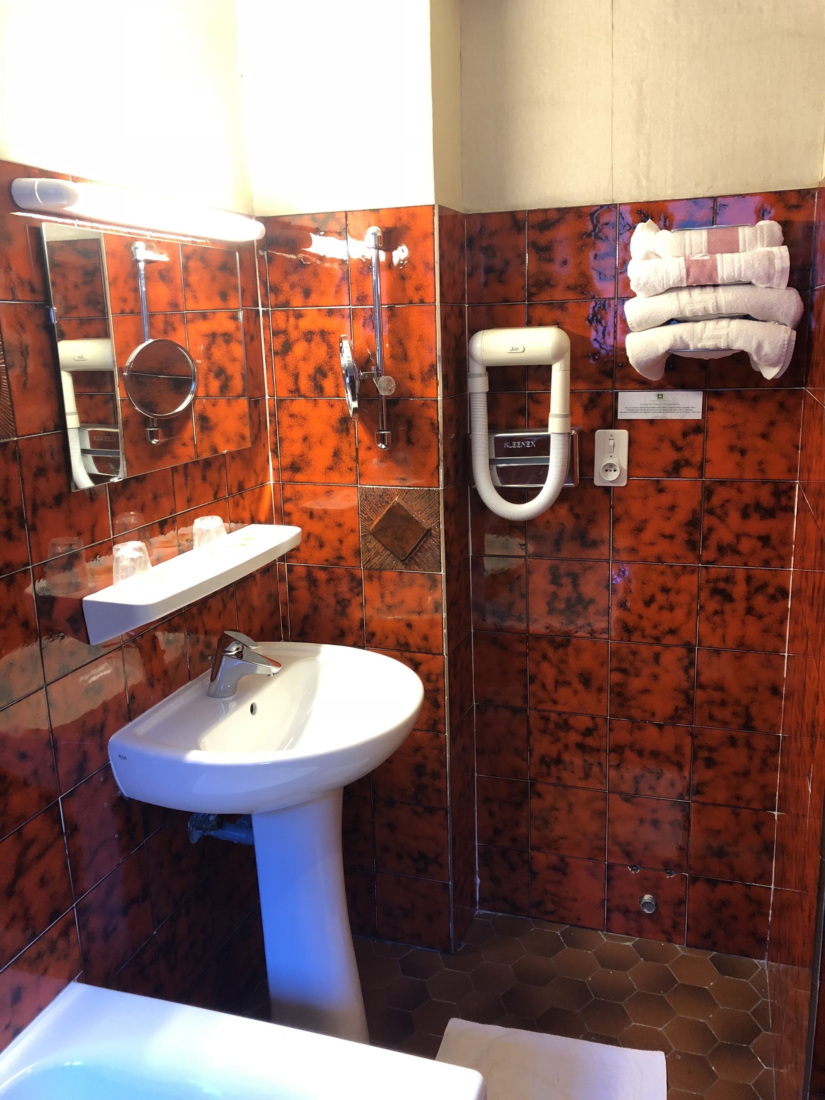 A bathroom with a white sink, mirror, and towel rack.