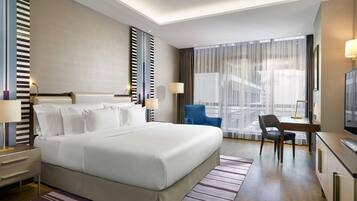 Una habitación de hotel con una cama grande, un escritorio, una silla y un televisor.