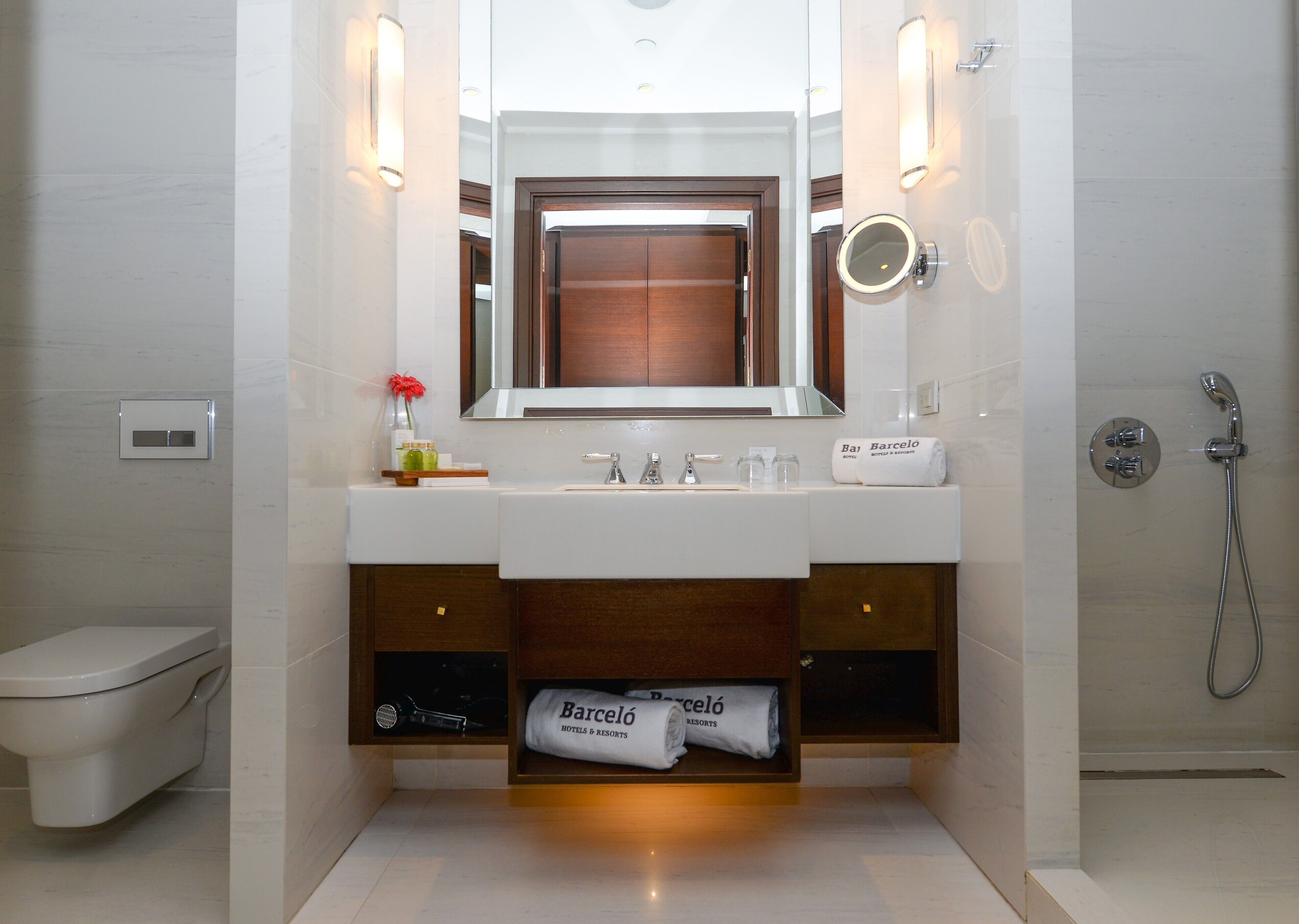 A modern bathroom with a white sink, a mirror, a towel rack, and a shower.