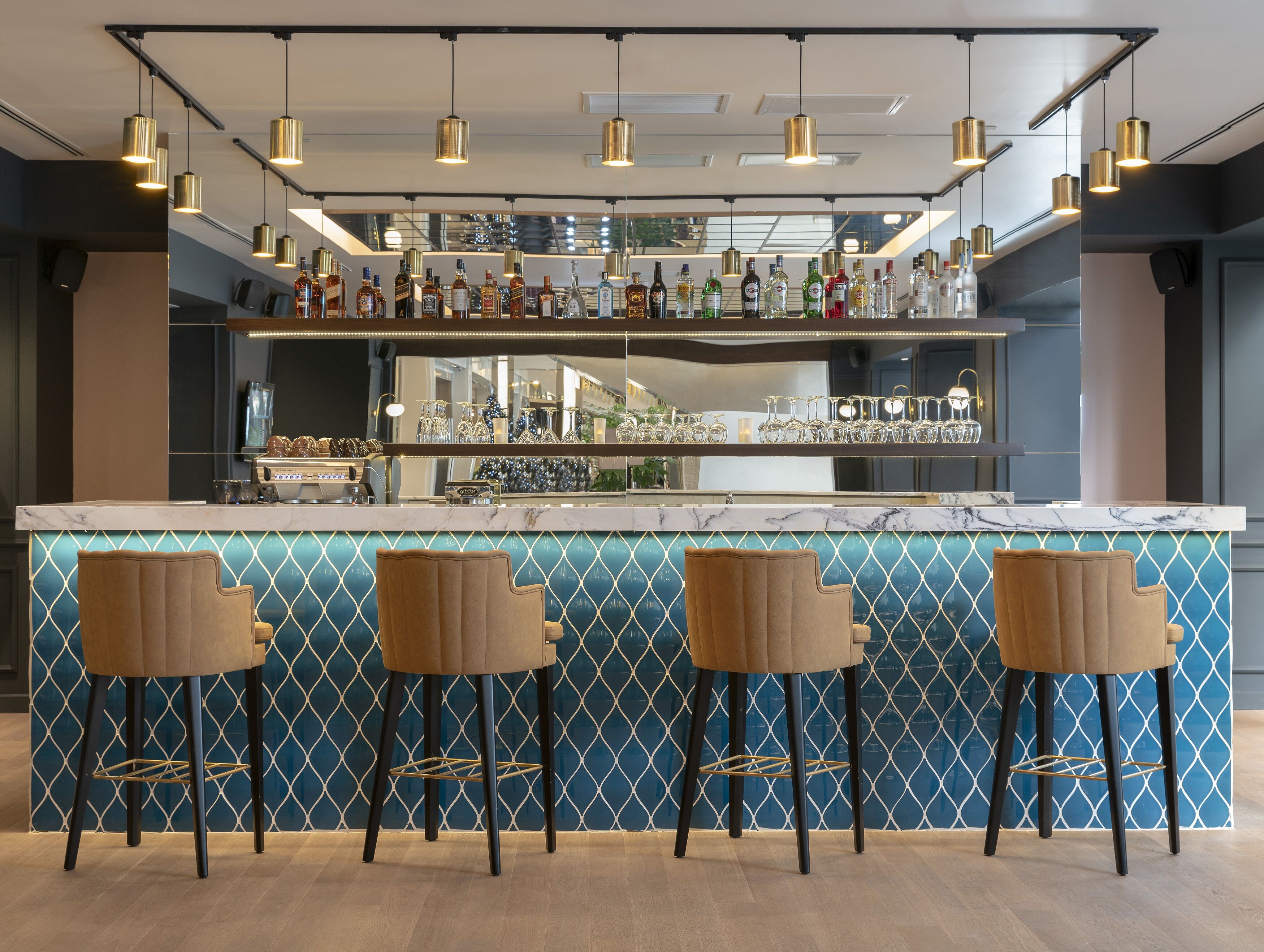 A bar area with a marble countertop, multiple bottles of liquor, and three bar stools.
