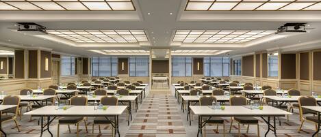 A large conference room with multiple tables and chairs, arranged in rows, with a high ceiling and large windows.