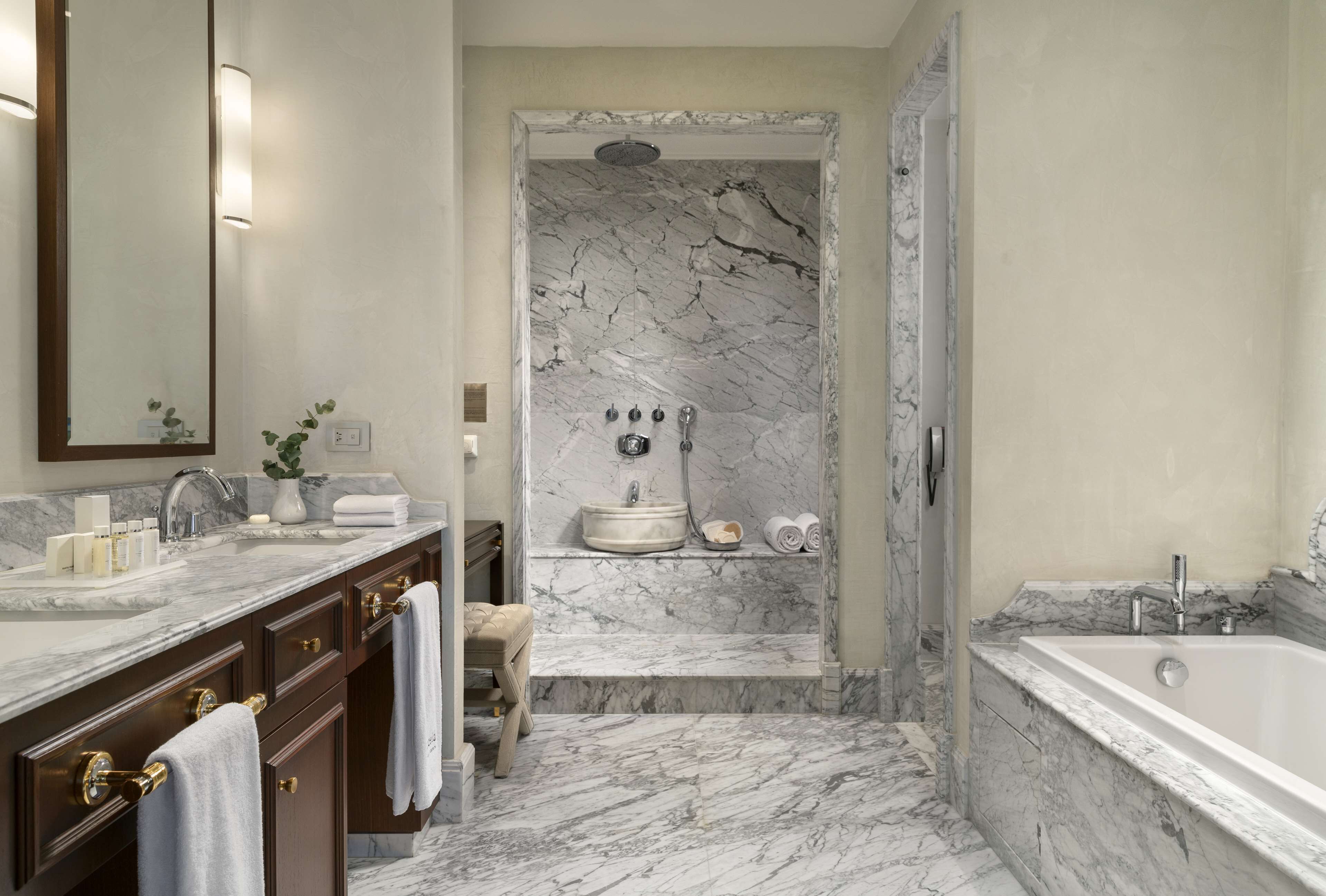 A bathroom with a marble sink, a bathtub, and a shower area.
