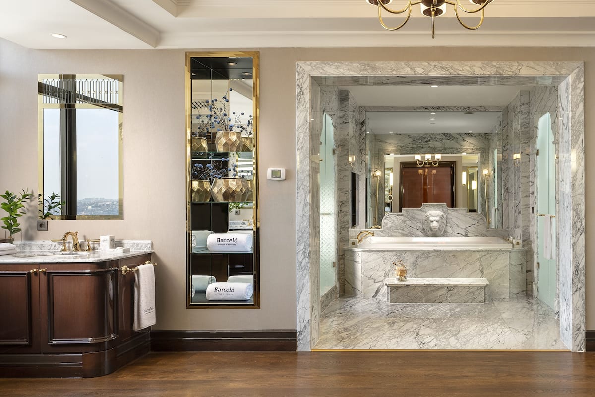 A luxurious bathroom with a marble sink, a large mirror, and a chandelier.
