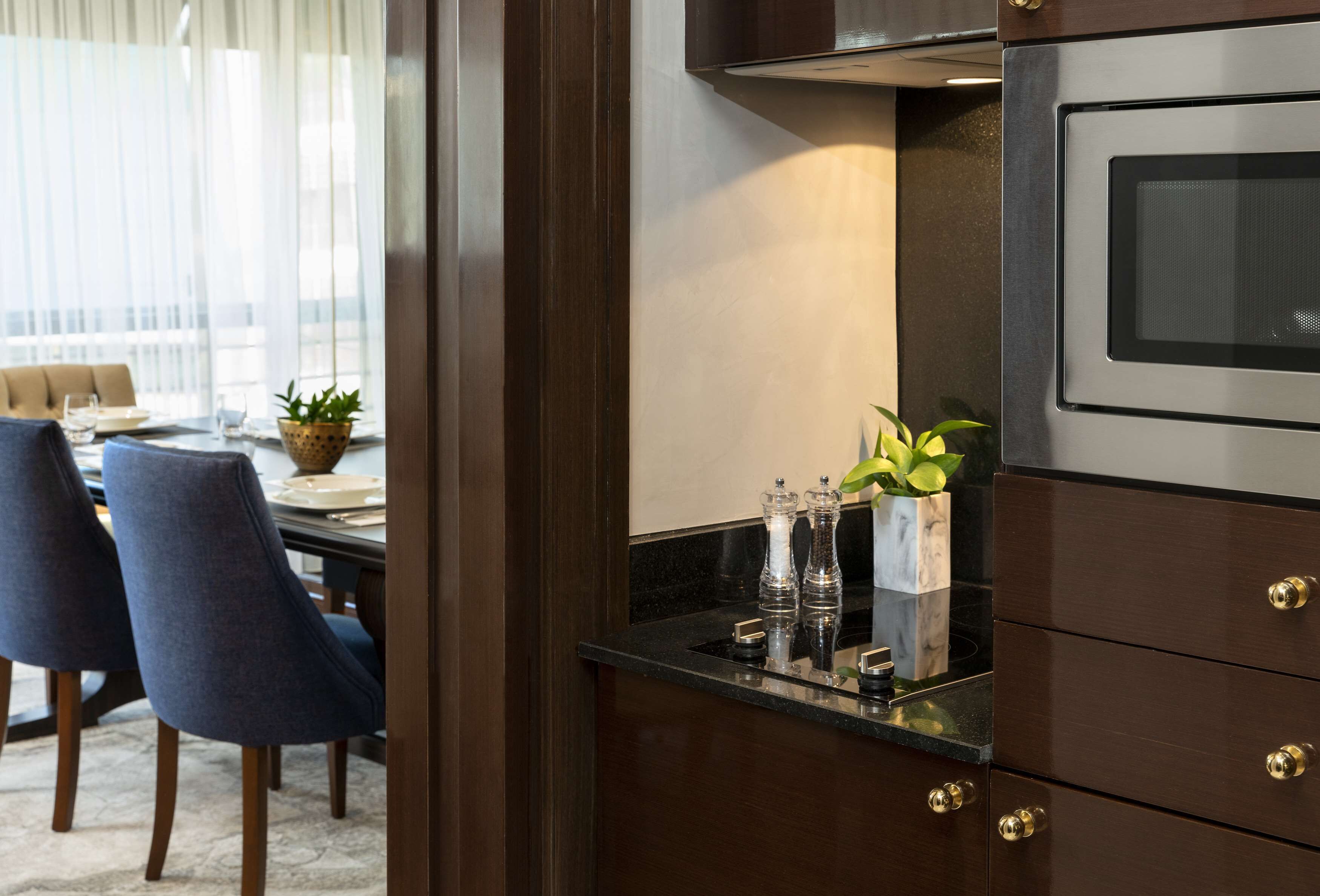 A modern kitchen with dark wood cabinets, a stainless steel oven, and a marble countertop.