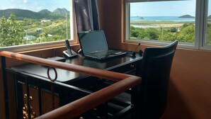 Habitació amb escriptori, portàtil i vista a un paisatge costaner.