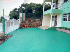 A residential building with a green lawn, a white fence, and a staircase leading to a balcony. - Cook's Estate (St. John's)