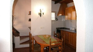 A kitchen with wooden cabinets, a stove, and a dining table with chairs. - 0538 Villa Efaistos en el Montgo (Denia)