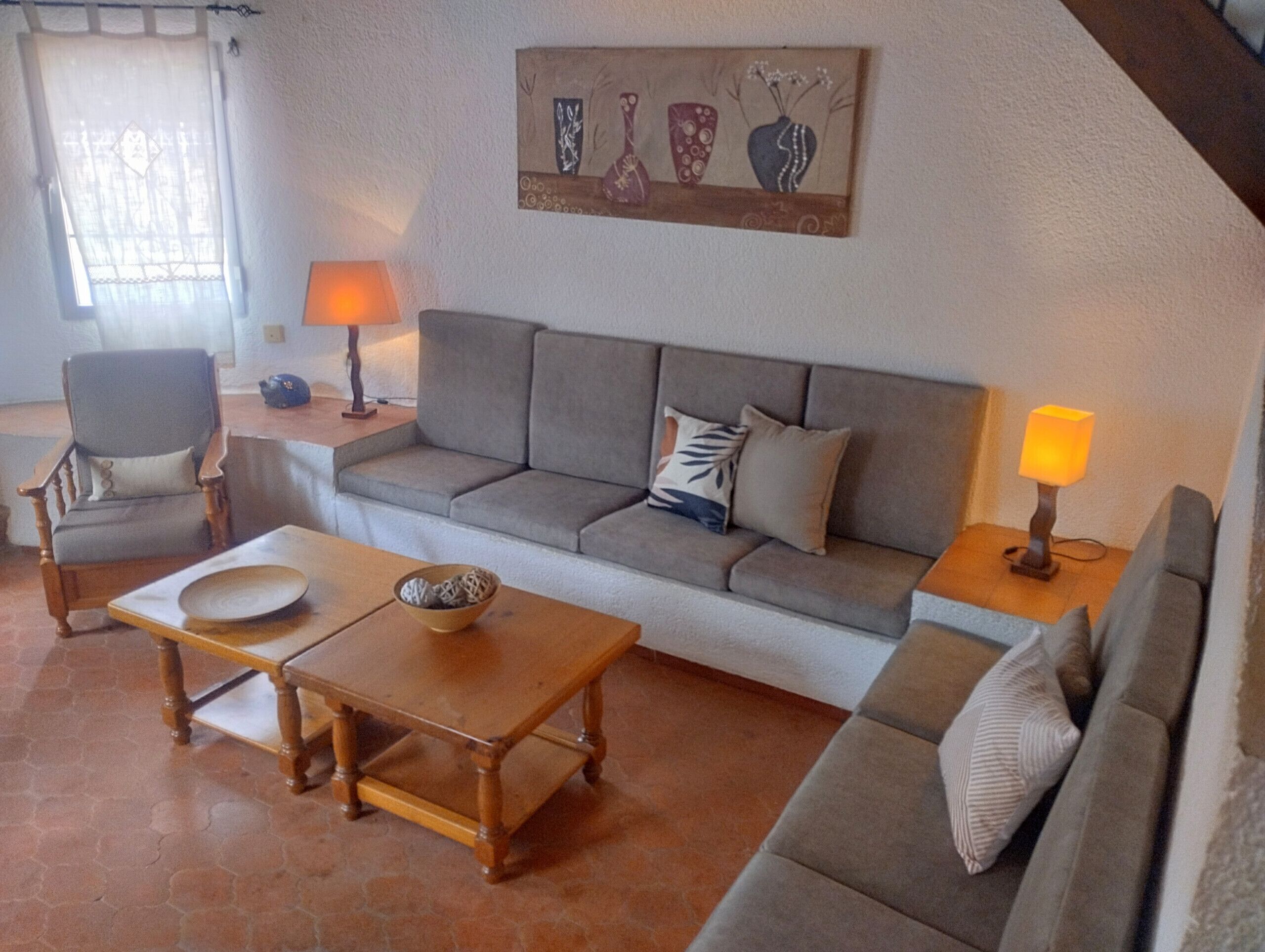 Ein Wohnzimmer mit einer Couch, Sesseln, einem Couchtisch und zwei Lampen.