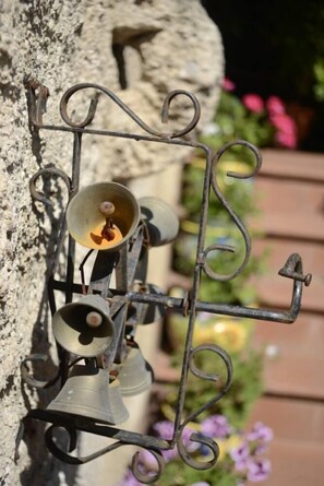 Un système de sonnerie métallique fixé au mur, composé de plusieurs cloches de différentes tailles.