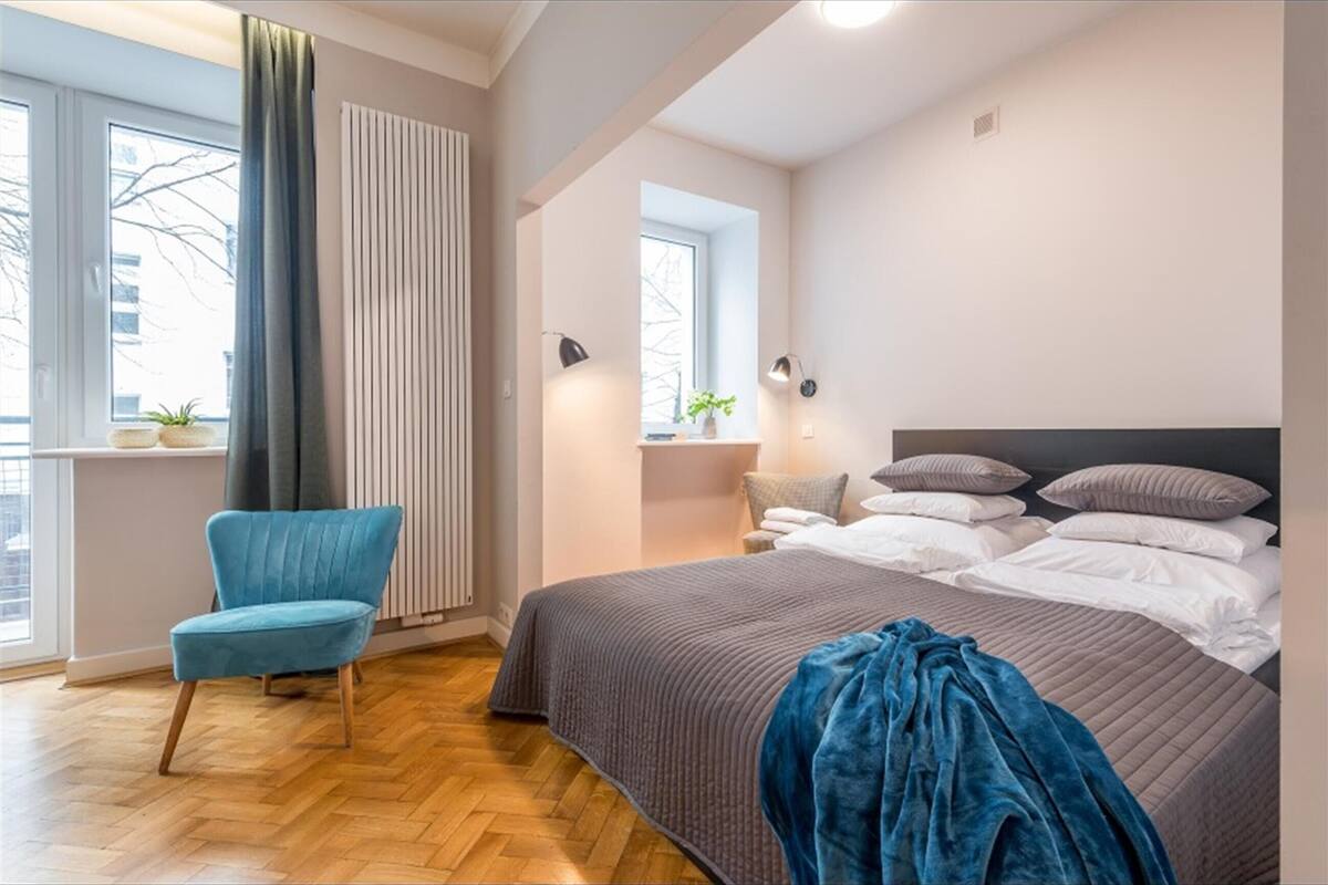 A bedroom with a bed, a chair, a window, and a radiator.