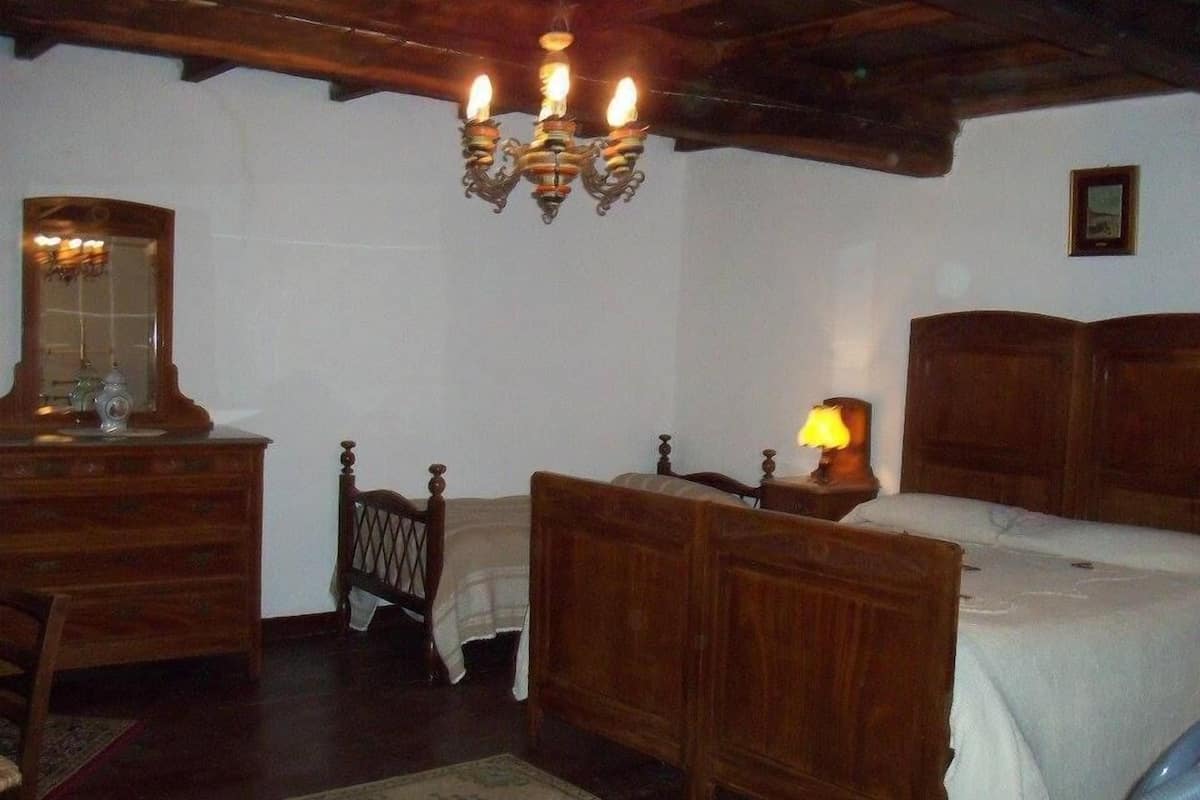 Een slaapkamer met een houten bed, een nachtkastje met een lamp, een dressoir en een spiegel.
