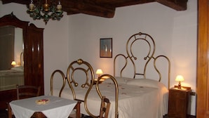 Een slaapkamer met een bed, een tafel, stoelen, een spiegel en een kroonluchter.