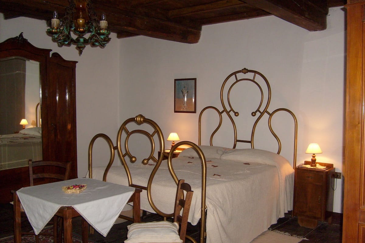 Een slaapkamer met een bed, een tafel, stoelen, een spiegel en een kroonluchter.