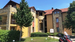 Un edificio residencial de varios pisos con balcones, fachada de piedra y techo de tejas rojas.