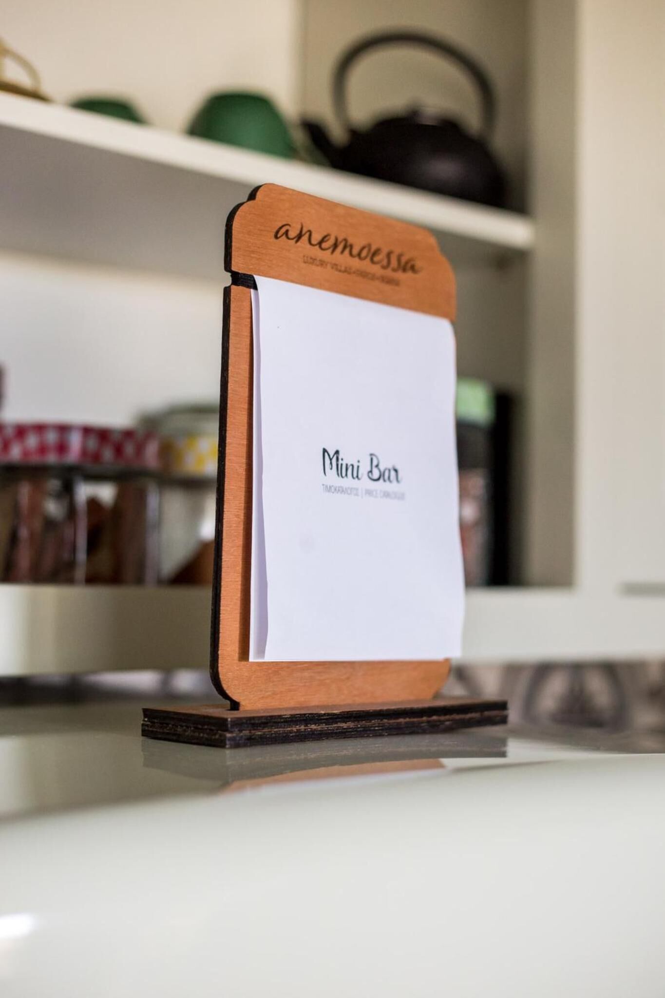 Un letrero de madera con 'anemossa' y 'Mini Bar' escrito, colocado sobre una mesa.